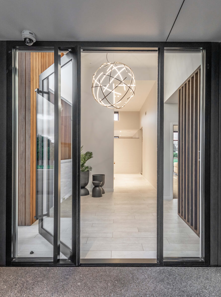 Duco entry door glass ceiling to floor, framed with 2 matching glass panels displayed in a house